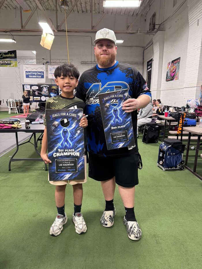 Jamie Graham holding Bags for a Cure charity tournament plaques with a young player